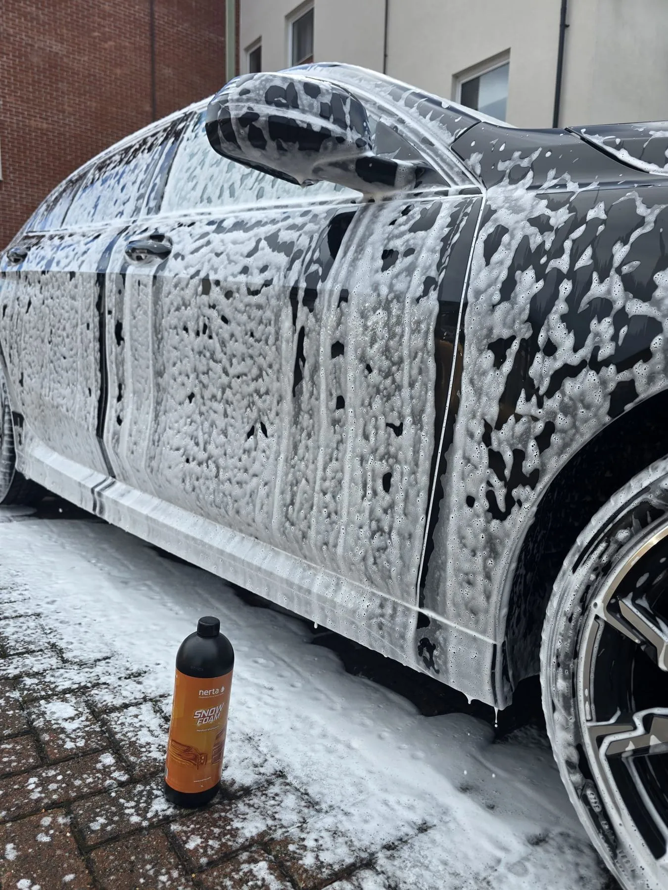 Nerta Snow Foam clinging to a black car door during pre-wash