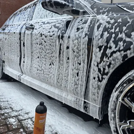 Nerta Snow Foam clinging to a black car door during pre-wash